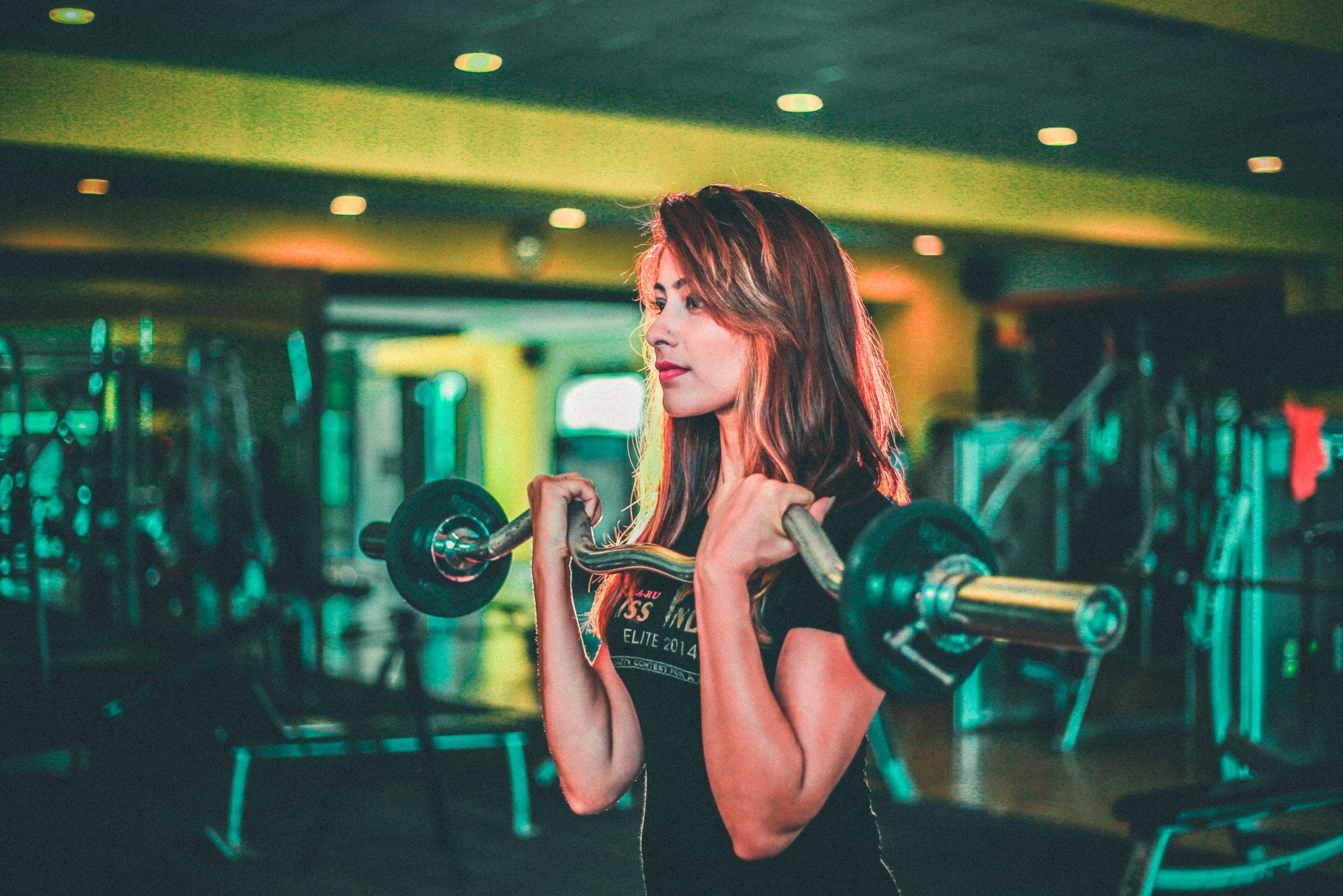 woman lifting light barbell in the gym