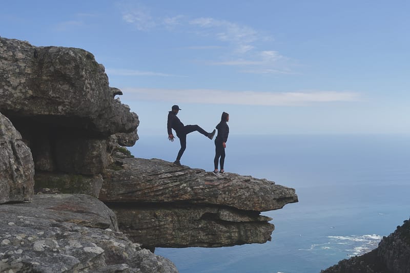 man pretending to kick lady of mountain