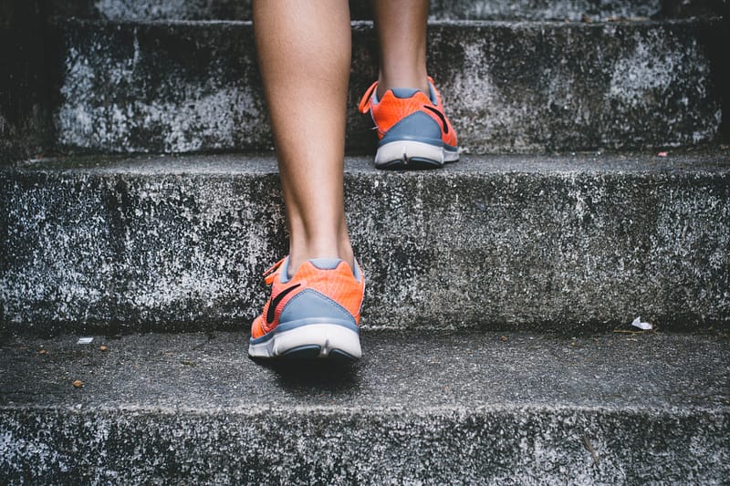 person in running shoes walking up grey steps